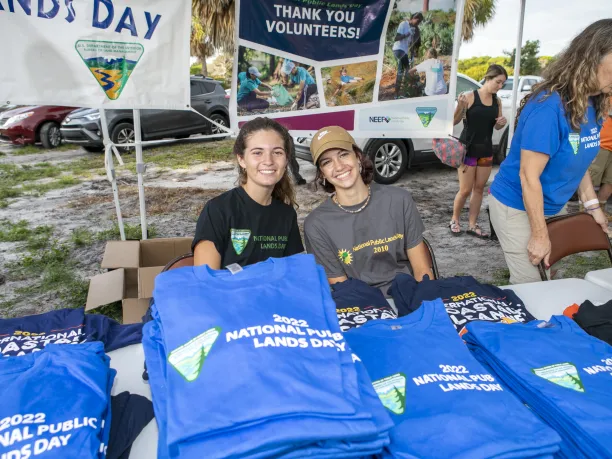 Smiling young people behind a table of shirts