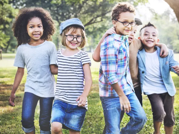 Children with their arms around each other, smiling, outdoors facing camera