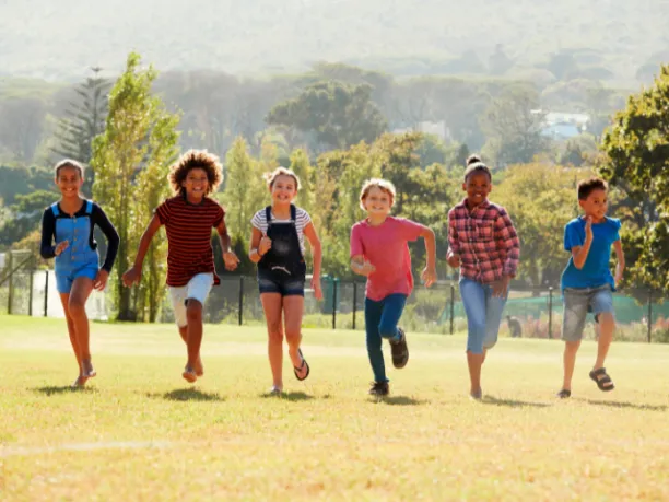 Kids running outdoors in a line towards the camera smiling