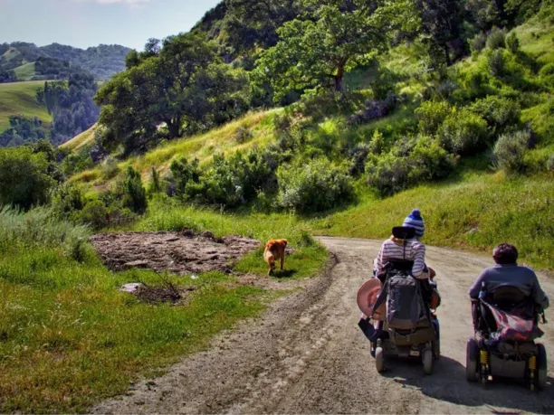 two women in all terrain electric wheelchairs on a trail in the San Francisco Bay area