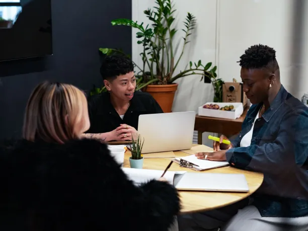 Three people sitting around a desk having a meeting