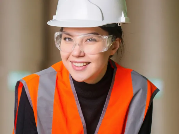 a young woman wearing a reflector vest and hard hat, employee of a manufacturing company