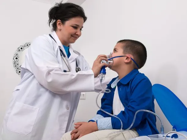 A female doctor holds an oxygen mask up to the face of a little boy