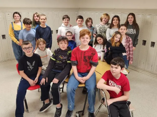 students sitting on a table and standing in a group smiling