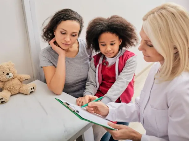 a female doctor fill out a form with a mother and daughter