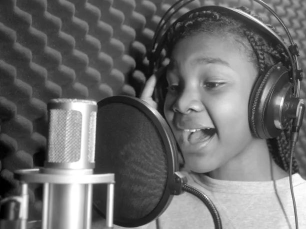 Heaven White, a young girl singing into a microphone with headphones on