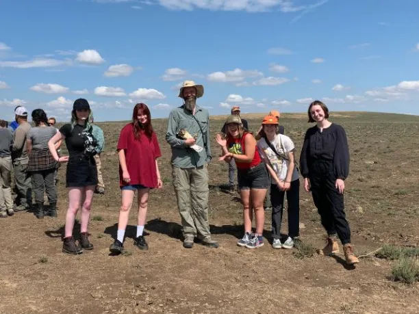 a Bureau of Land Management Biologist holds a raptor with a group of students during a Greening STEM Project