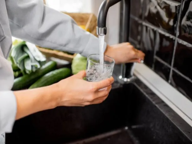 a person fills a glass of water from the kitchen sink tap