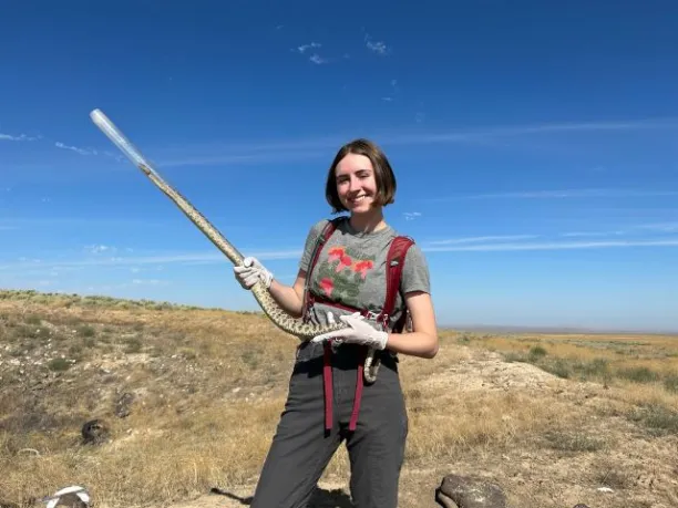 Student Abella Cathey, holds a snake while during a STEM conservation field project.