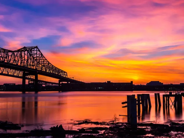 A view of a bridge over the Mississippi River in New Orleans at sunset.