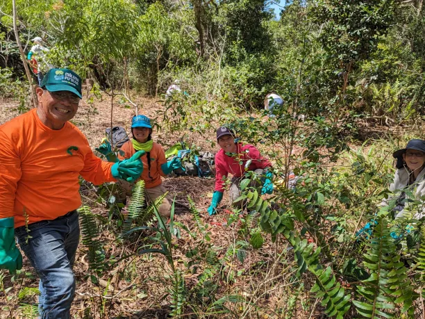 Volunteers from Army Natural Resources Program Hawaii – Schofield Barracks taking a break from removing invasive bushes to pose for a photo