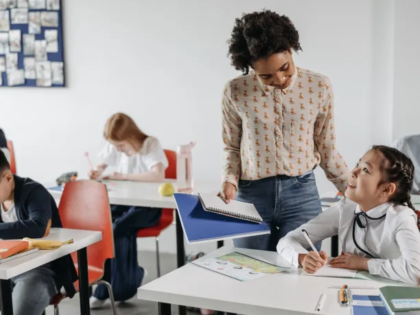 a teacher speaks to a student at her desk