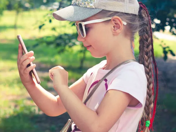 a young girl uses a cellphone outside
