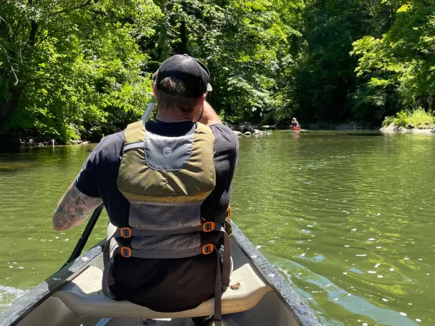 a veteran paddles a canoe on a river in the forest