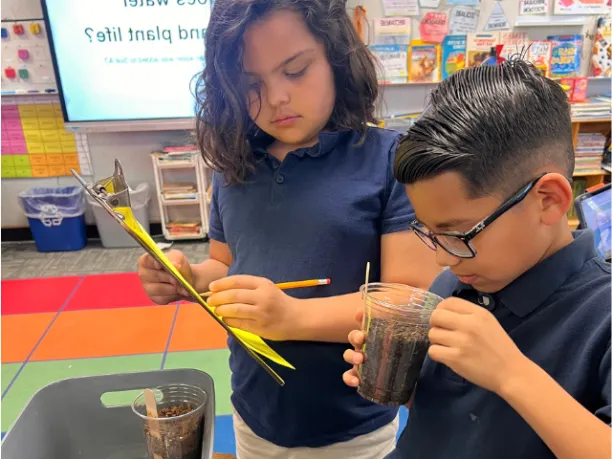 Two middle school kids looking closely at a science experiment