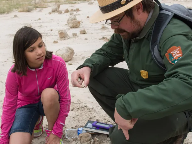 Park ranger and middle school girl examining a rock in the Badlands