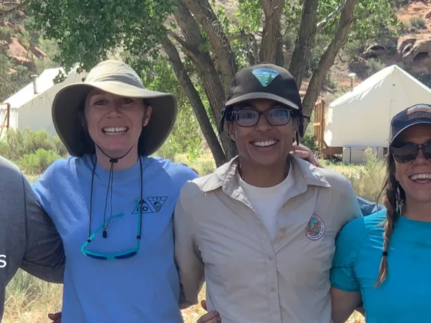 Photo of Bureau of Land Management and nonprofit partners arm in arm smiling.