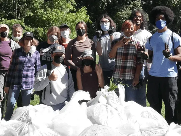 photo of group standing in front of pile of trash bags after a clean-up.