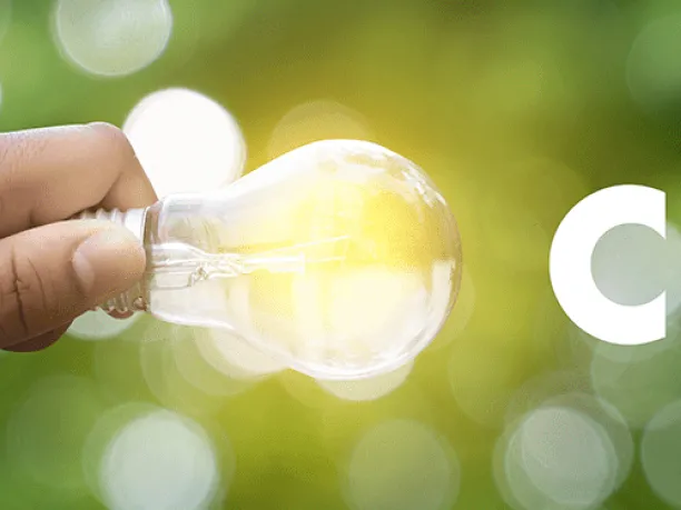 Photo of young hand holding a lightbulb with the letters CSR to the right and green in background