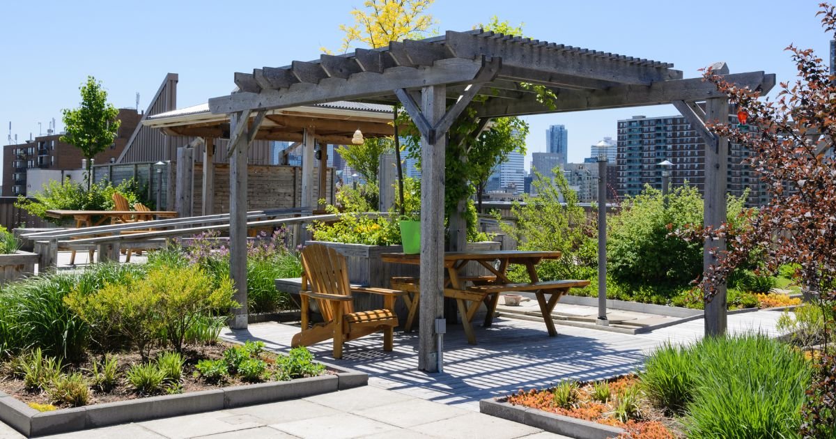 a green roof top with gardens and sitting area in a city landscape