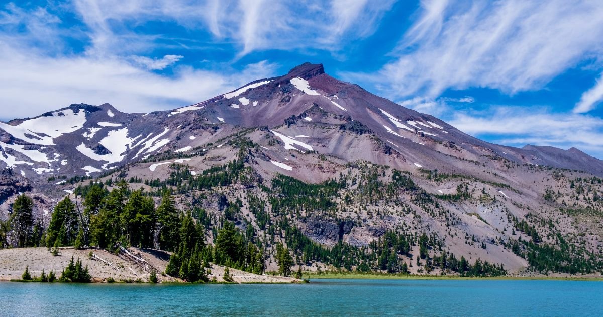 small patches of snow sit on the side of a mountain top with exposed dirt
