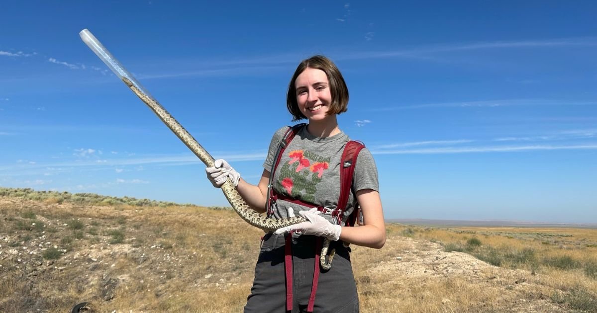 Student Abella Cathey, holds a snake while during a STEM conservation field project.