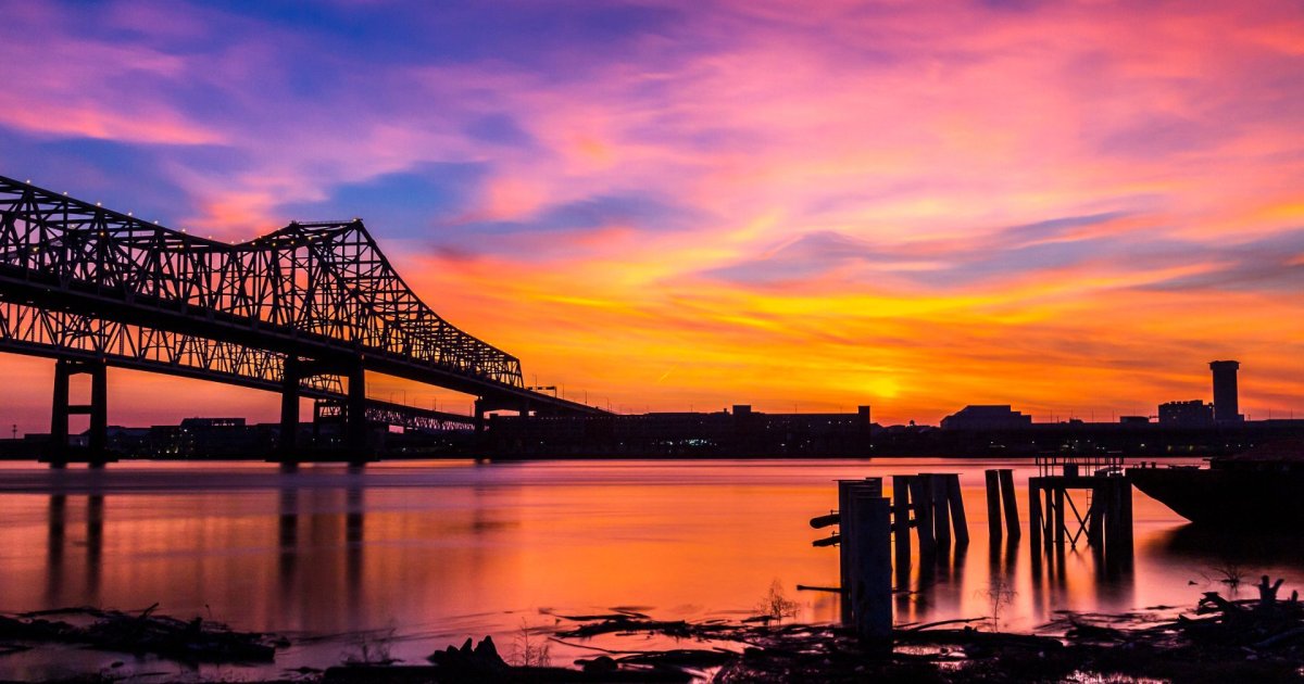 A view of a bridge over the Mississippi River in New Orleans at sunset.