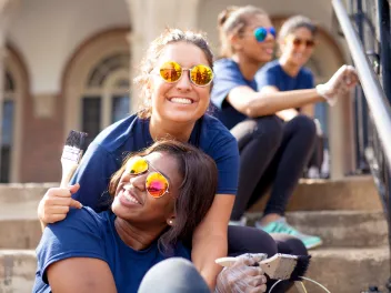 Two young women on stairs painting and smiling