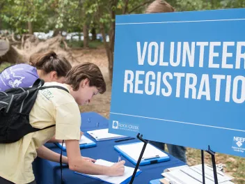 People signing up near a volunteer registration sign