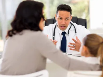 Doctor talking to mother and child across a desk