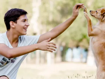 Teen boy playing with dog outdoors