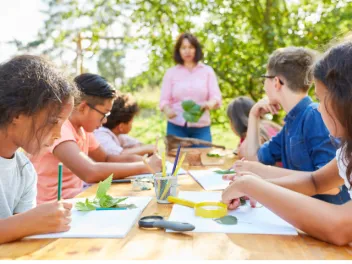 Teacher outside with students at a table 