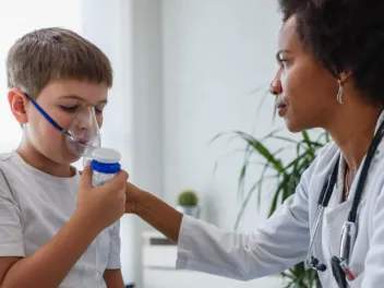 Pediatrician helps young boy with breathing device