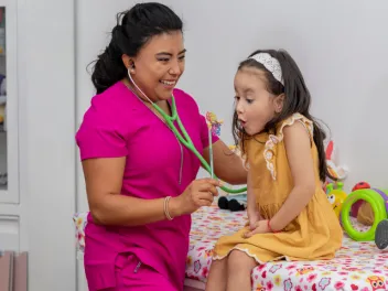 Pediatrician with young patient blowing a pinwheel