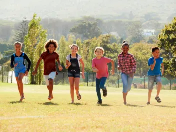 Kids running outdoors in a line towards the camera smiling