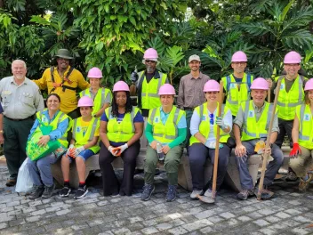 A group of National Public Lands Day volunteers in reflector vests sit for a group picture at El Yunque National Forest in Puerto Rico