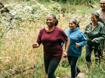 A group of older people walk on a path through a forest