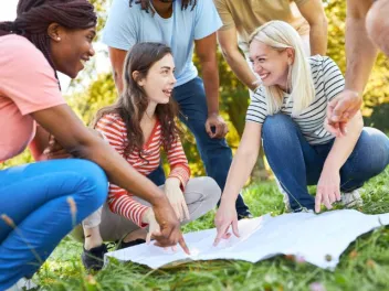 a group of people outside pointing to a large paper making a plan