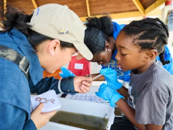 Woman in hat helping young girl with water samples