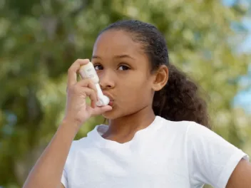 young girl using asthma inhaler outside