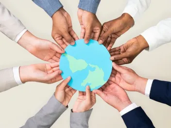 hands of different colors create a circle and hold an image of the Earth