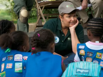 An educator speaks with a group of girl scouts at a volunteer event