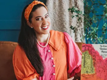 Artist Lindsay Cordero sits holding her picture book The Krewe of Barkus and Meoux