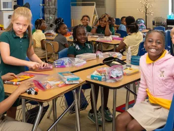 middle school students sit in a group around desks smiling
