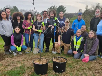 students from McCaskey high school stand near two trees ready for planting