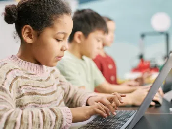 a young girl uses a computer in a classroom