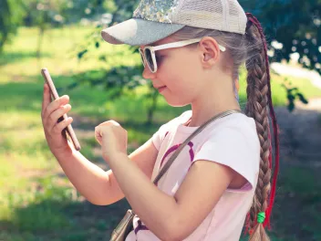 a young girl uses a cellphone outside
