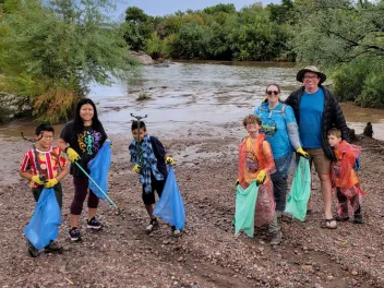 families volunteer on National Public Lands Day collecting trash on a riverbank