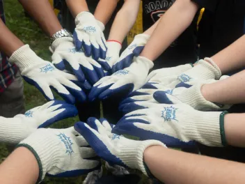 a group of volunteers put their hands together in a circle before an activity 