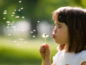 Girl blowing dandelion 